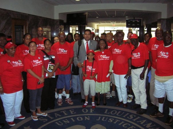 Group photograph of ACORN New Orleans members wearing red T-shirts that say, “Raise Wages!” (photo credit: Tanya Harris-Glasow or Marie Hurt).