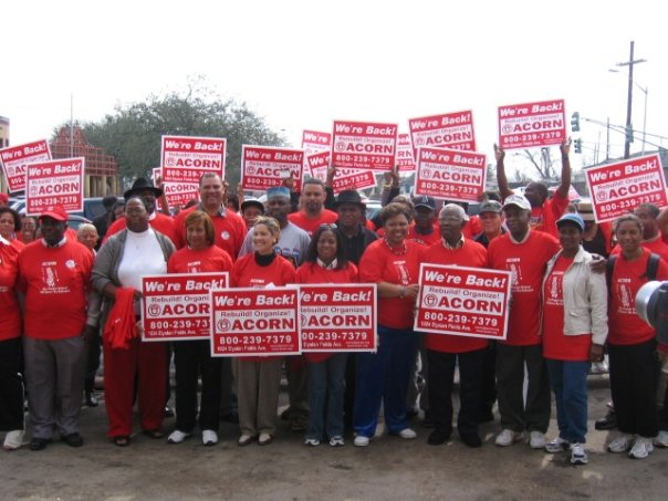 Group photograph of New Orleans members in the wake of Hurricane Katrina wearing red T-shirts and holding signs that read, “We’re Back! Rebuild! Organize! ACORN” (photo credit: Tanya Harris-Glasow or Marie Hurt).