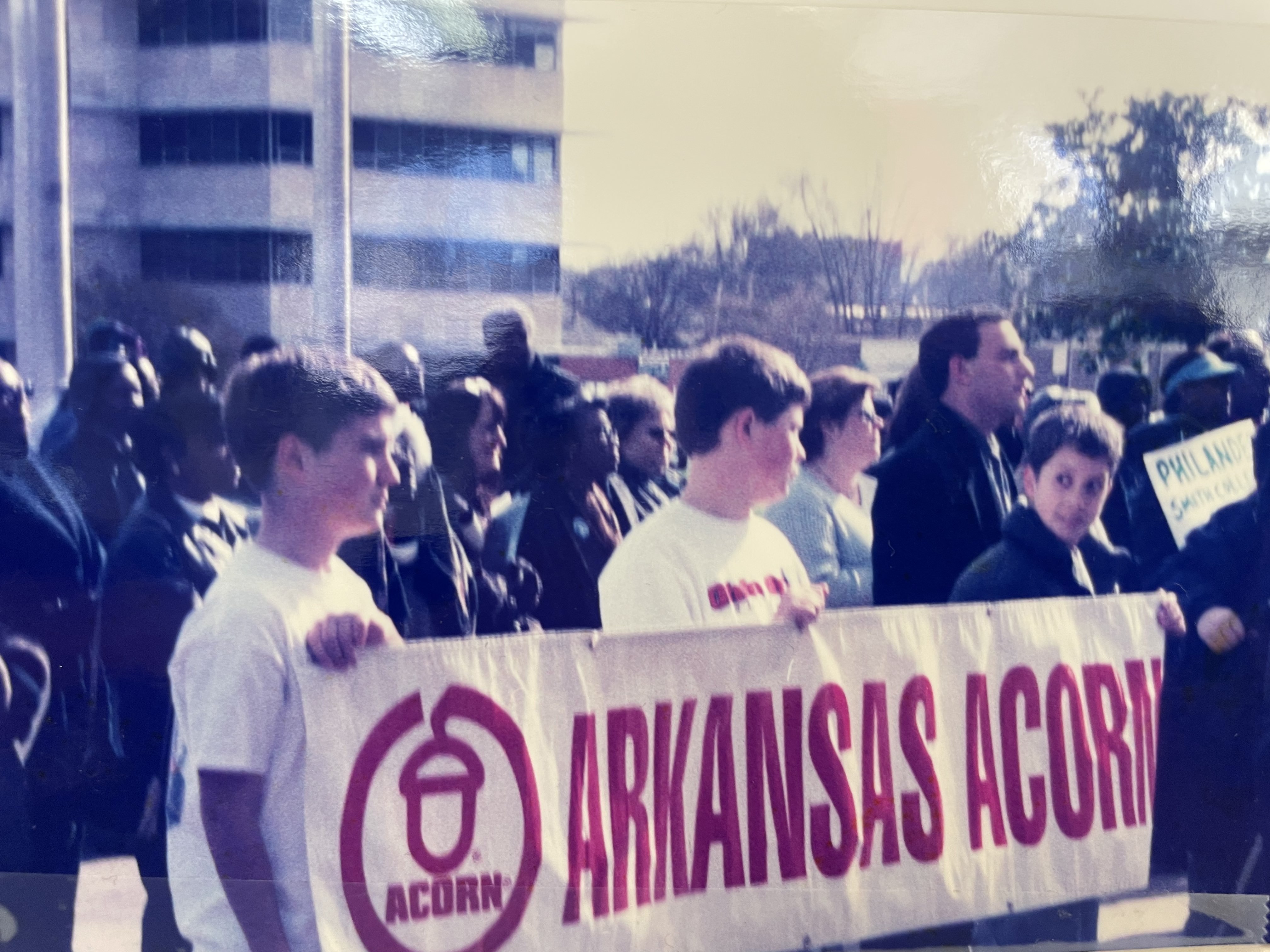 Photograph from the Arksansas Community Organizations (ACO) office in Little Rock, Arkansas, featuring an ACORN action where a group of kids are holding up a banner that reads, “ARKANSAS ACORN”.