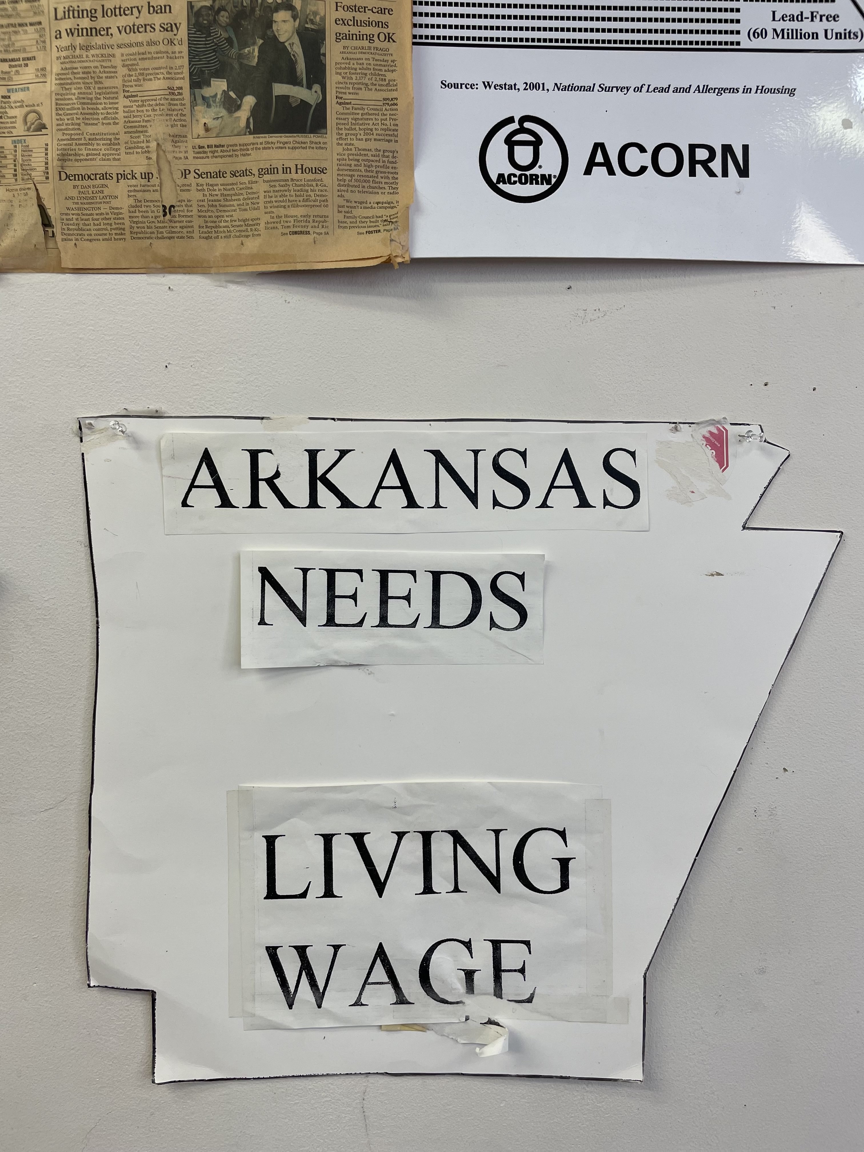 Poster hanging on the wall at the Arkansas Community Organizations (ACO) office in Little Rock, Arkansas. It’s cut in the shape of the state of Arkansas and reads “Arkansas Needs Living Wage”.